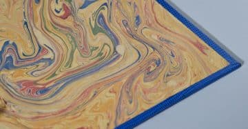 Detalle de portamenú con diseño marmolado en tonos azul, amarillo y rojo – Papelgráfico